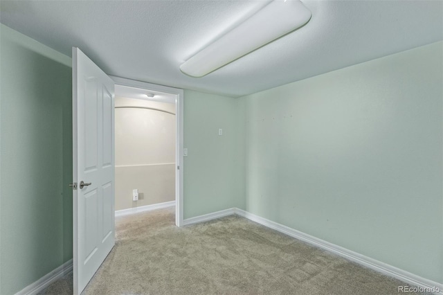 spare room featuring light carpet and baseboards