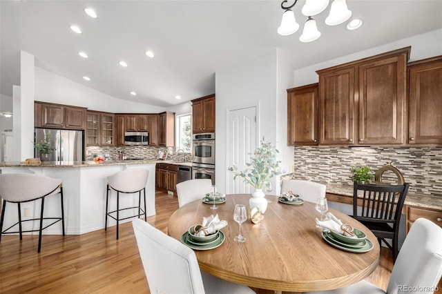 dining room featuring lofted ceiling, a chandelier, light wood finished floors, and recessed lighting