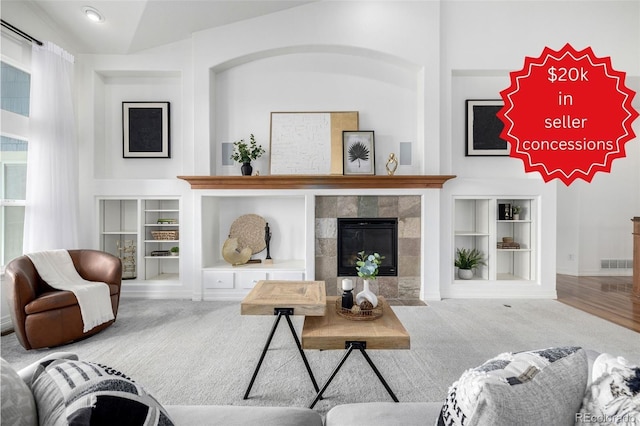 carpeted living room with built in features, a fireplace, and baseboards