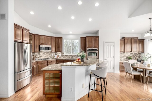 8802 E 148th Ln, Thornton, CO 80602 - kitchen featuring stainless steel appliances, a center island, decorative backsplash, a kitchen breakfast bar, and light stone counters