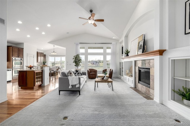 8802 E 148th Ln, Thornton, CO 80602 - living area with lofted ceiling, a tiled fireplace, ceiling fan, recessed lighting, and light wood-type flooring
