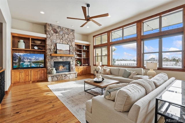 living room featuring ceiling fan, a fireplace, light hardwood / wood-style floors, and built in features