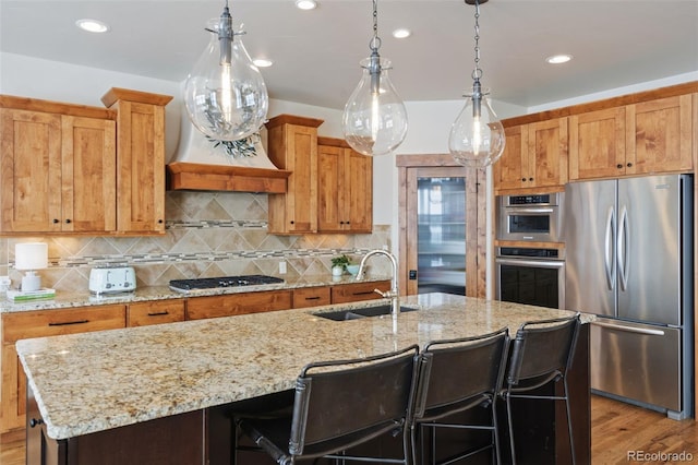 kitchen with sink, a center island with sink, a breakfast bar, and appliances with stainless steel finishes