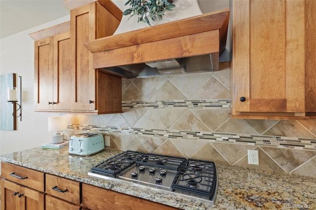 kitchen with custom exhaust hood, light stone countertops, stainless steel gas cooktop, and decorative backsplash