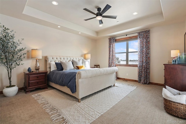 bedroom with ceiling fan, a raised ceiling, and light carpet