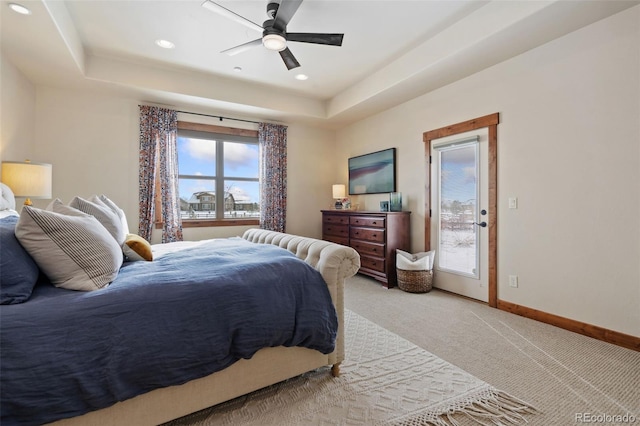 bedroom with ceiling fan, carpet flooring, a tray ceiling, and access to exterior