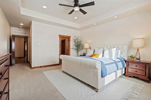 carpeted bedroom featuring ceiling fan and a tray ceiling