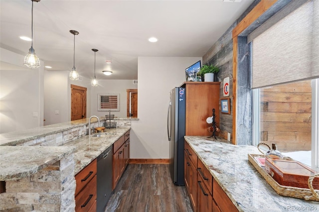 kitchen featuring appliances with stainless steel finishes, pendant lighting, sink, dark hardwood / wood-style flooring, and light stone counters