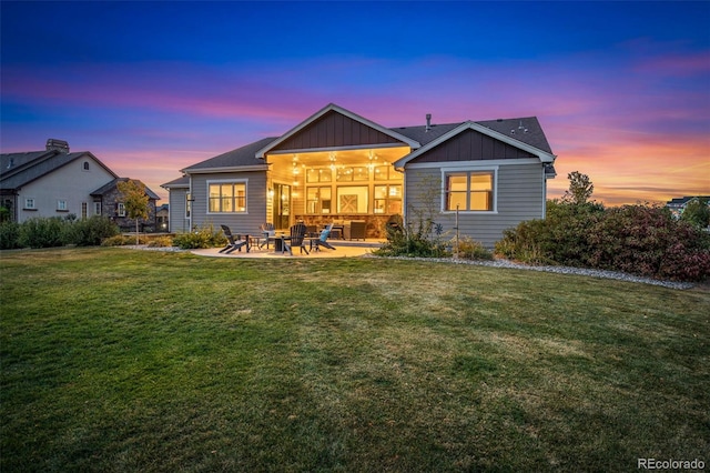 back house at dusk featuring a yard, ceiling fan, and a patio area