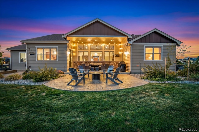 back house at dusk with an outdoor fire pit, a yard, and a patio