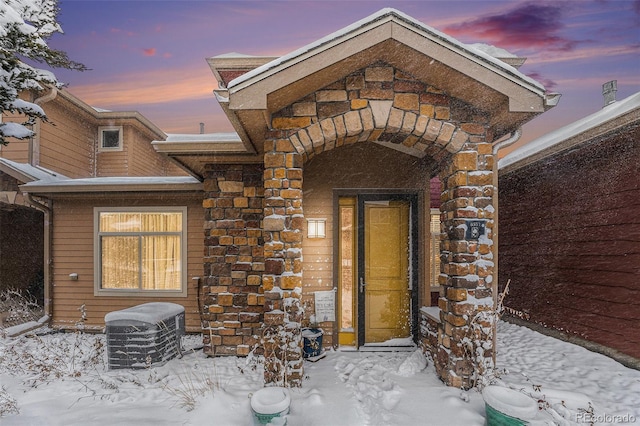 snow covered property entrance featuring central AC unit