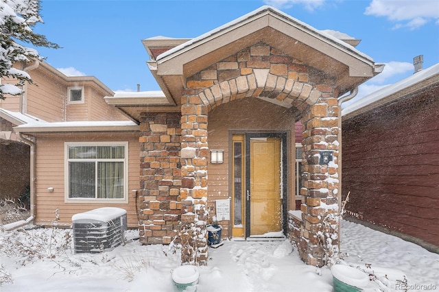 snow covered property entrance featuring central AC