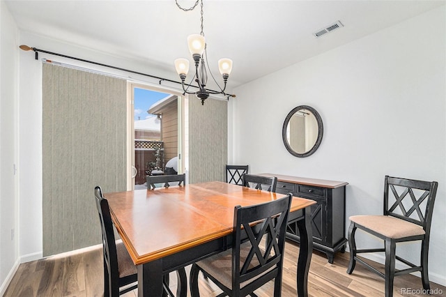 dining space with hardwood / wood-style floors and an inviting chandelier