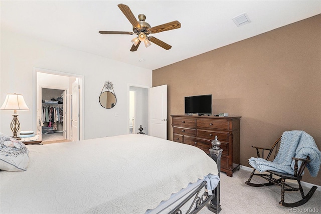 bedroom with a walk in closet, ceiling fan, a closet, and light colored carpet