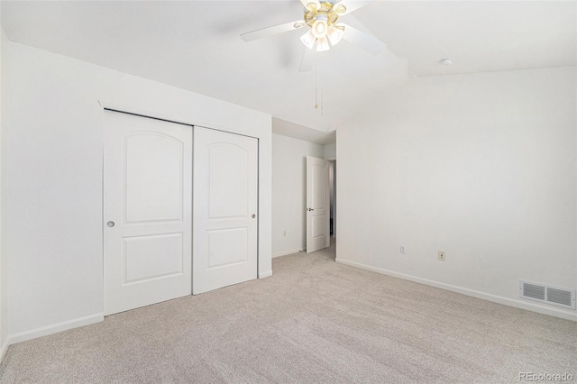 unfurnished bedroom featuring ceiling fan, light colored carpet, and a closet