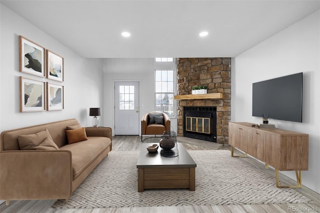 living room with a fireplace, light wood-style flooring, and recessed lighting