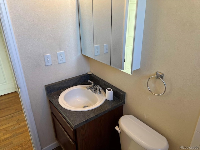 bathroom with vanity, toilet, and hardwood / wood-style floors