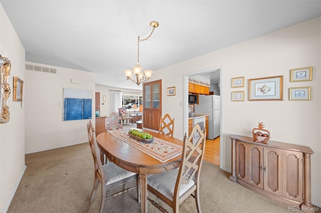 dining area featuring light carpet, a notable chandelier, and visible vents