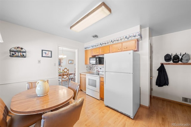 kitchen featuring baseboards, light brown cabinetry, light wood-style flooring, a notable chandelier, and white appliances