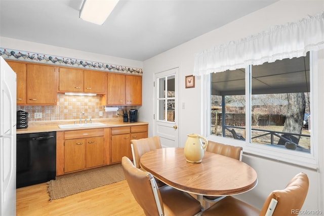 kitchen featuring light wood finished floors, a sink, light countertops, dishwasher, and backsplash