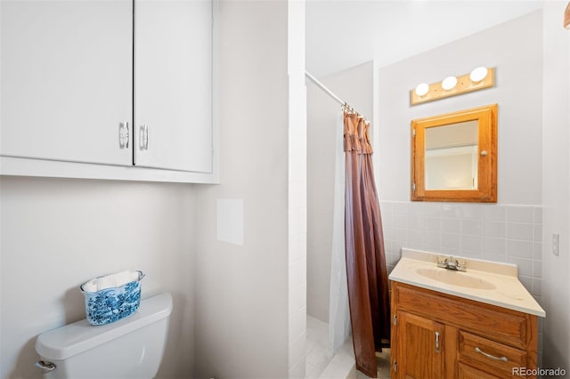 bathroom featuring toilet, tile walls, a stall shower, and vanity