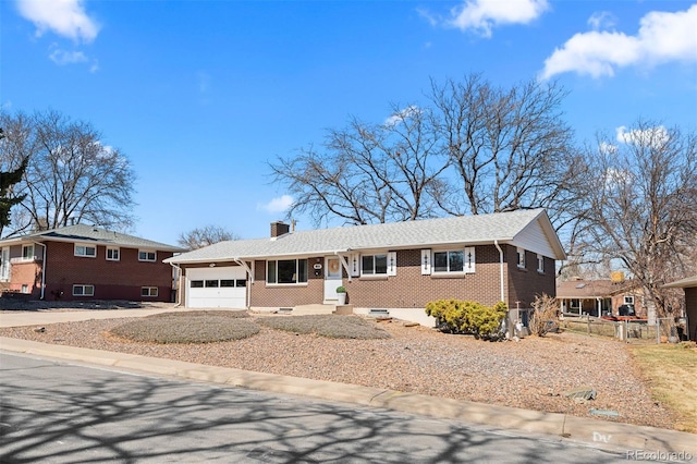 view of front of home with driveway, fence, a garage, brick siding, and a chimney