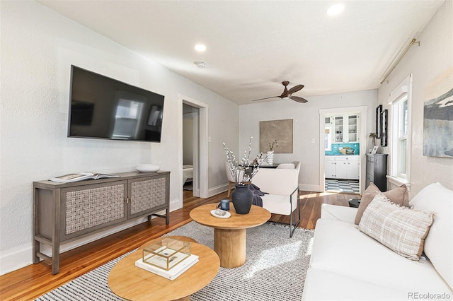 living area featuring recessed lighting, a ceiling fan, baseboards, and wood finished floors