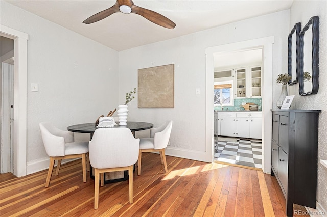 dining area with light wood-style flooring, a ceiling fan, and baseboards