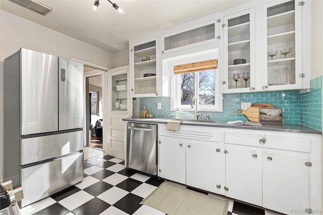 kitchen with tasteful backsplash, visible vents, tile patterned floors, stainless steel appliances, and a sink