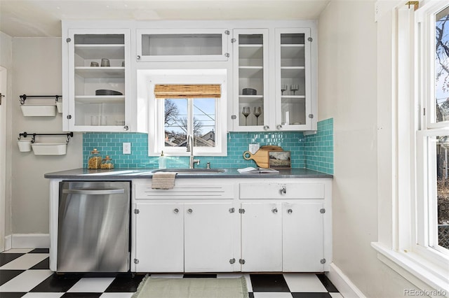 kitchen with tile patterned floors, stainless steel dishwasher, a sink, and white cabinetry