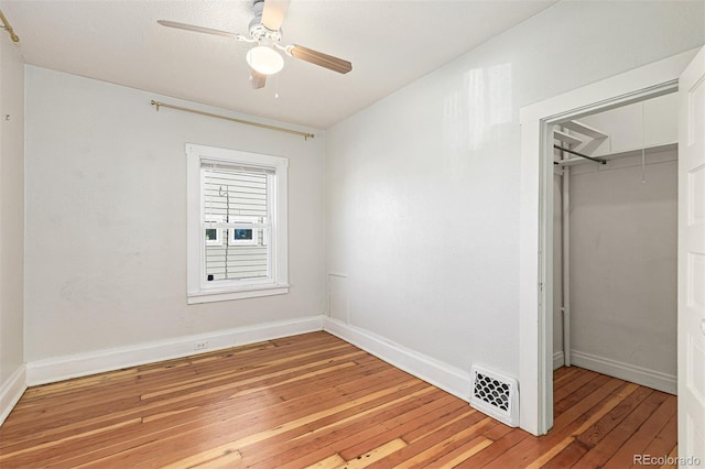 unfurnished bedroom featuring light wood finished floors, visible vents, baseboards, attic access, and a closet