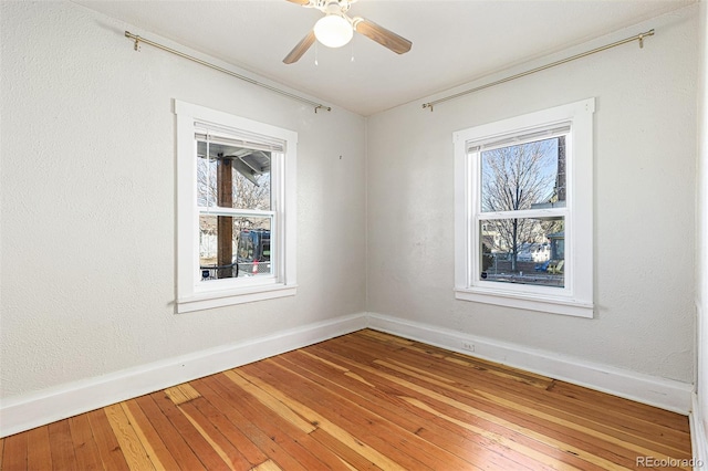 empty room with baseboards, a ceiling fan, and light wood finished floors