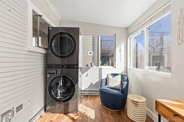 washroom with stacked washer and clothes dryer and wood finished floors