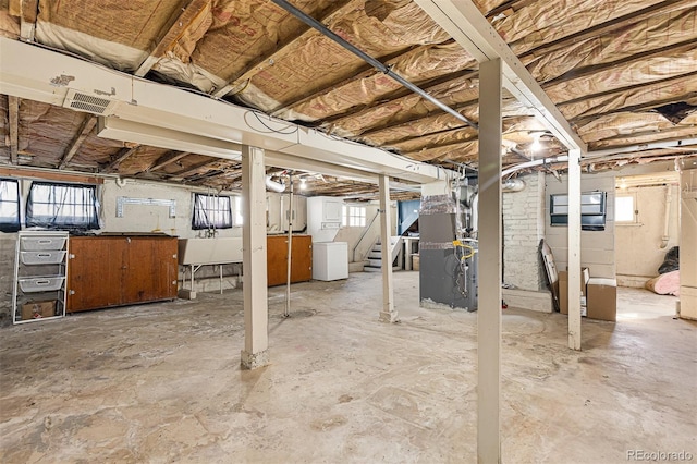 below grade area with heating unit, stairway, a healthy amount of sunlight, and a sink