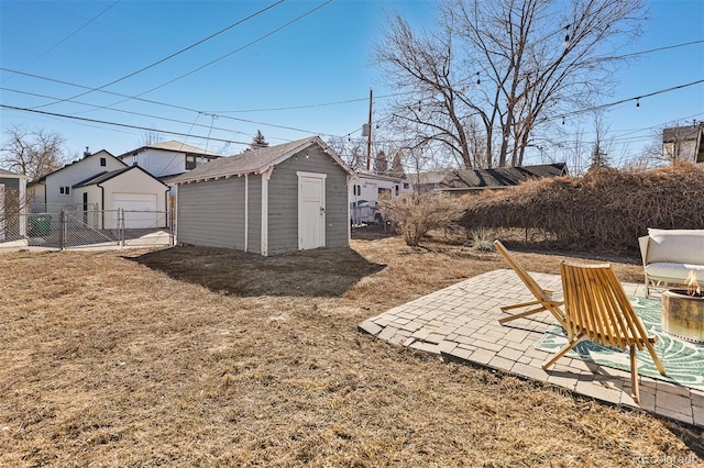 view of yard featuring a detached garage, fence, a storage shed, an outdoor structure, and a patio