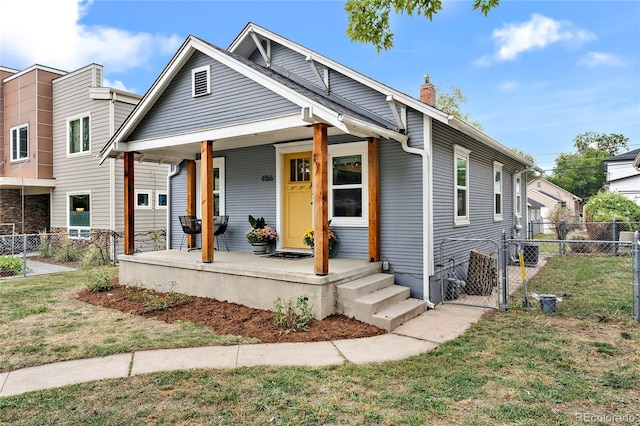 view of front of property featuring a front lawn, fence, a porch, a chimney, and a gate