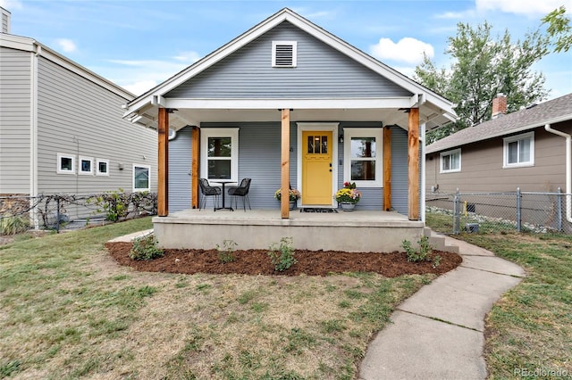 view of front of house featuring a porch, fence, and a front lawn