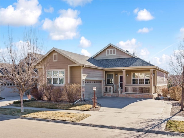 view of front of property featuring a shingled roof, concrete driveway, covered porch, a garage, and stone siding