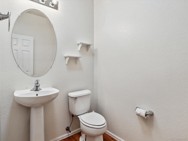 bathroom featuring a sink, baseboards, toilet, and wood finished floors