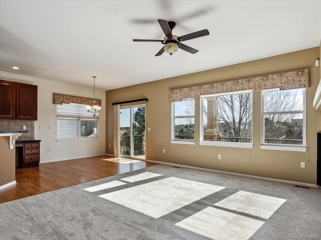 unfurnished living room featuring visible vents, baseboards, carpet floors, recessed lighting, and ceiling fan with notable chandelier