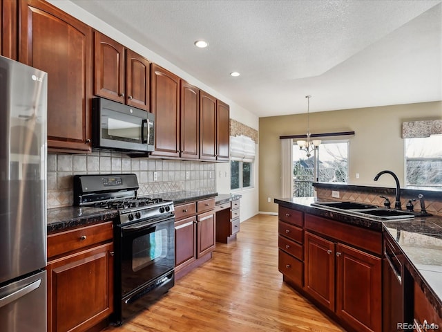 kitchen with light wood-style flooring, a sink, freestanding refrigerator, decorative backsplash, and black range with gas stovetop