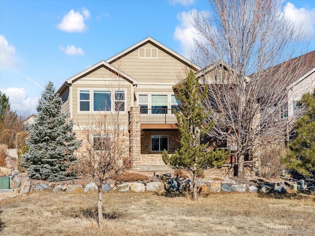 rear view of house with a balcony and stone siding