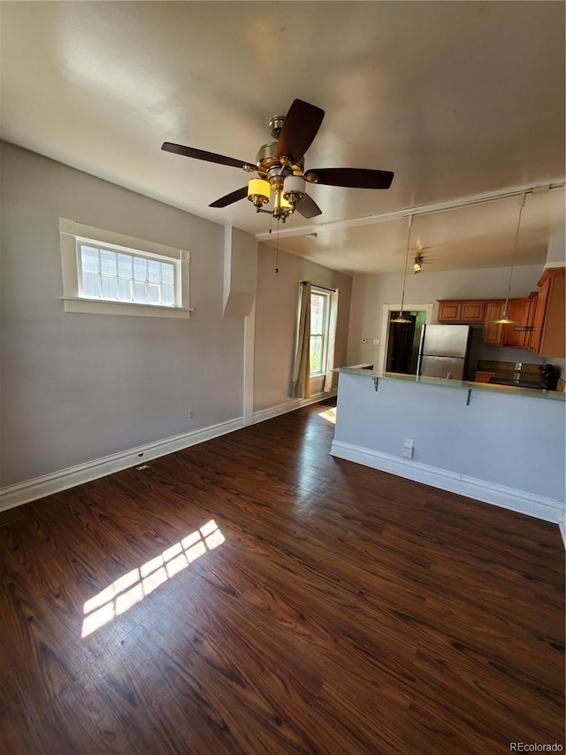 unfurnished living room with dark hardwood / wood-style flooring, ceiling fan, and a healthy amount of sunlight