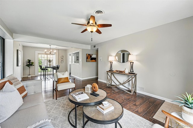 living area featuring baseboards, ceiling fan with notable chandelier, wood finished floors, and visible vents