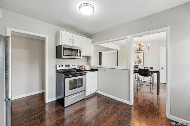 kitchen with an inviting chandelier, appliances with stainless steel finishes, white cabinets, and dark wood finished floors