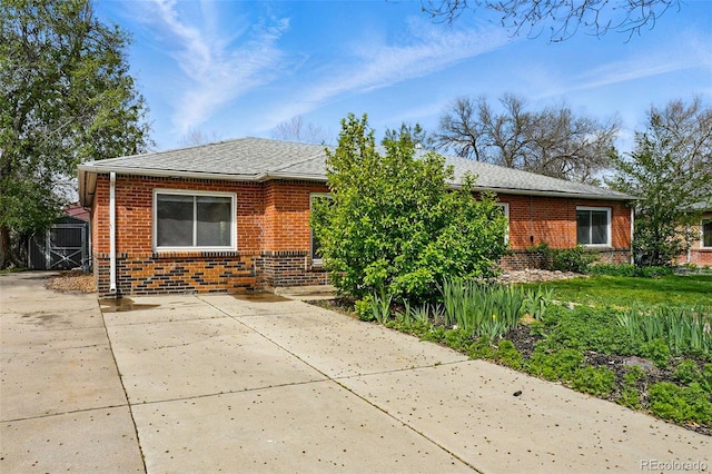 view of front of home with brick siding and roof with shingles