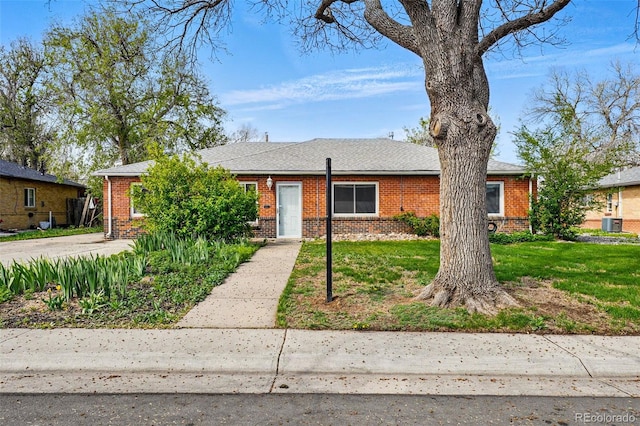 view of front facade with central air condition unit, a front yard, and brick siding