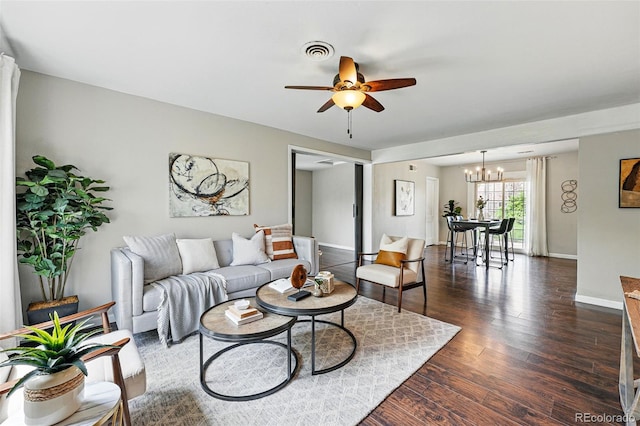 living area featuring baseboards, visible vents, dark wood-style floors, and ceiling fan with notable chandelier