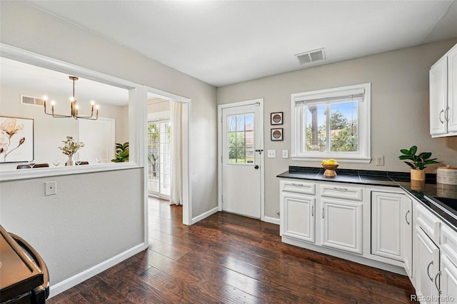kitchen featuring dark countertops, dark wood-type flooring, a chandelier, and visible vents