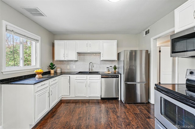 kitchen featuring stainless steel appliances, visible vents, dark wood-style floors, and a sink